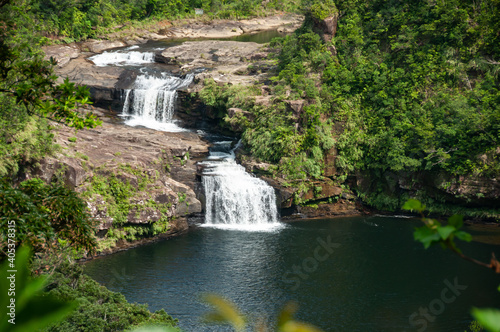 Waterfall with two falls in the middle of the jungle of Iriomote island with a beautiful natural pool and tropical vegetation around.