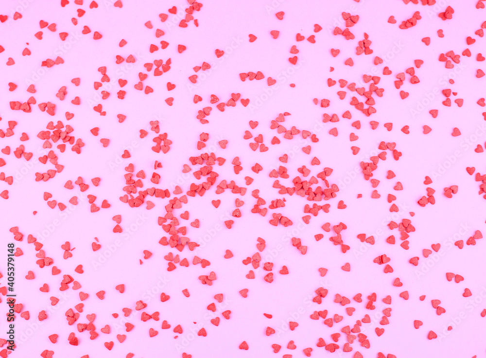 red sprinkling confectionery in the form of hearts on pink background