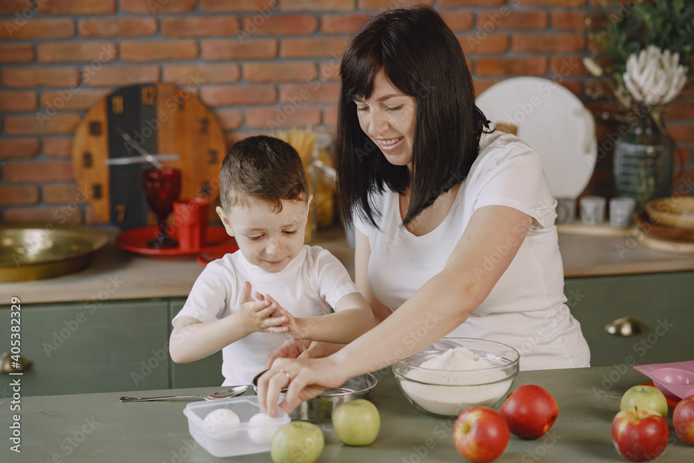Fototapeta premium Family in a kitchen. Beautiful mother with little son. Little boy playing wit a dough.