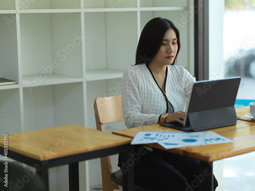 Businesswoman working with digital tablet and business document on wooden table