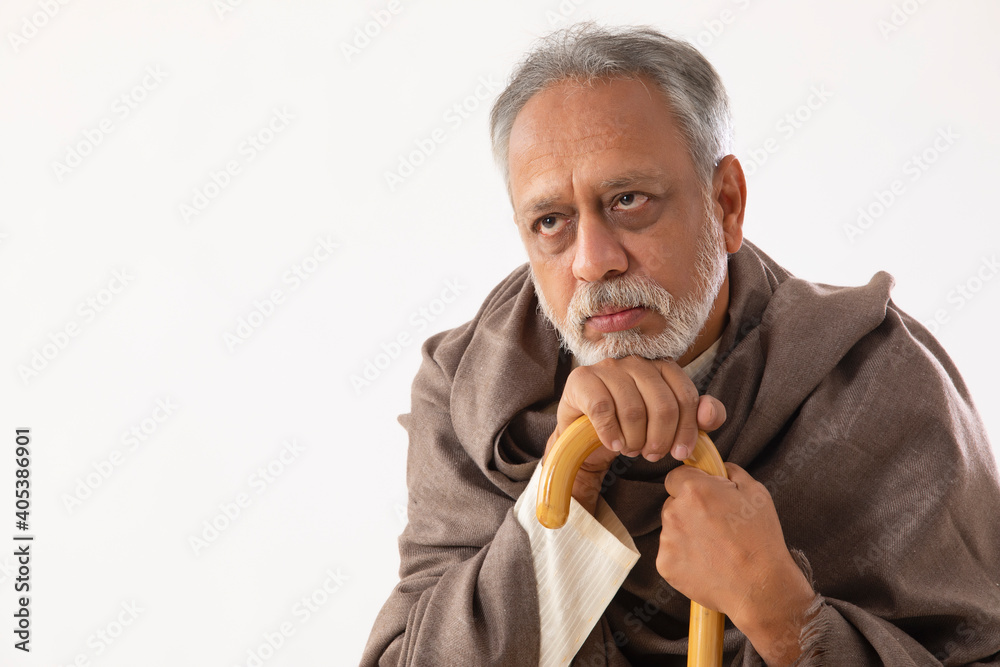 A SENIOR ADULT MAN HOLDING WALKING STICK SITTING IN DESPAIR A SENIOR ADULT MAN HOLDING WALKING STICK SITTING IN DESPAIR