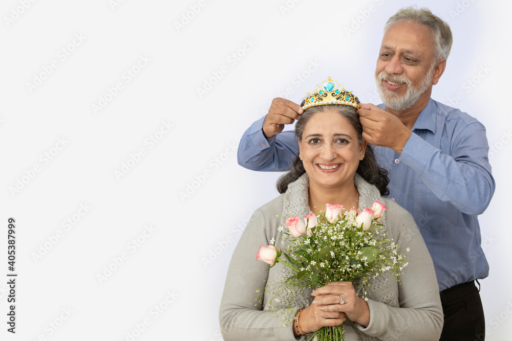 A SENIOR ADULT WOMAN SITTING WITH HUSBAND CROWNING HER HAPPILY A SENIOR ADULT WOMAN SITTING WITH HUSBAND CROWNING HER HAPPILY