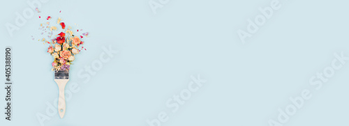 Brush paints with flowers, spring concept on pastel blue background. Minimal nature flat lay banner