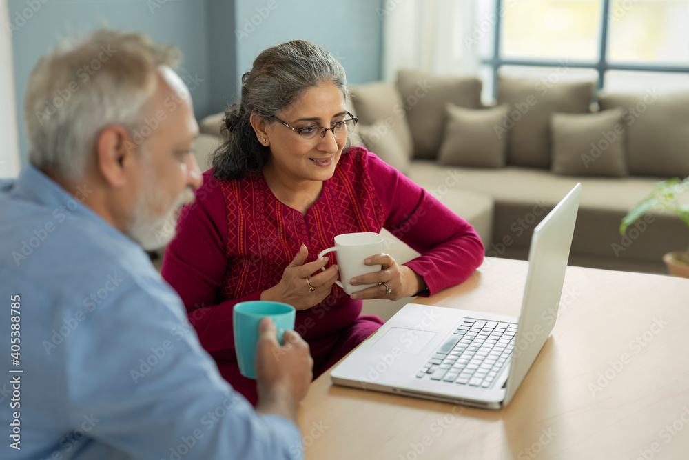 Fototapeta premium A SENIOR ADULT WOMAN AND HUSBAND LOOKING AT LAPTOP TOGETHER 
