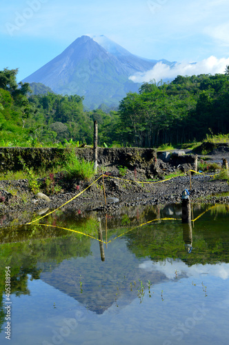 Merapi volcano with its reflection from small puddle