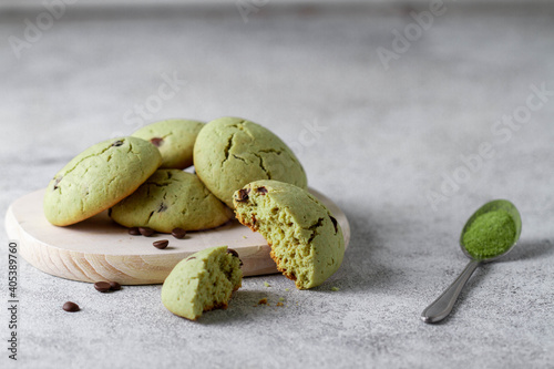 Biscuits with matcha tea and chocolate drops, next to a spoon with powder.