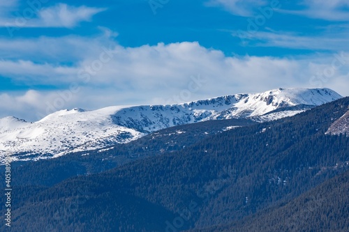 Beautiful winter panoramic natural mountain landscape. Attractive snowy peaks of Rila Mountains, Bulgaria. White clouds in dynamic blue sky, perfect conditions for tourism recreation and winter sports © Miglena Pencheva