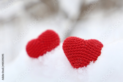 Valentine hearts in winter forest. Two red knitted hearts on snow  symbol of romantic love  background for holiday