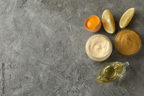 Jar with mayonnaise and ingredients for cooking on gray background, top view
