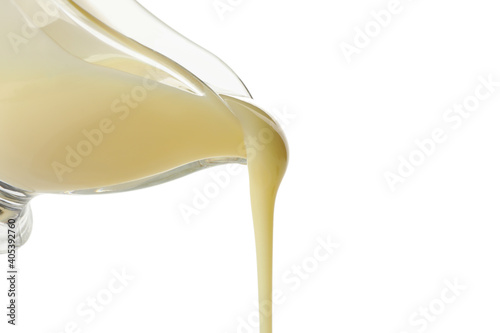 Condensed milk is pouring from the gravy boat, isolated on white background photo