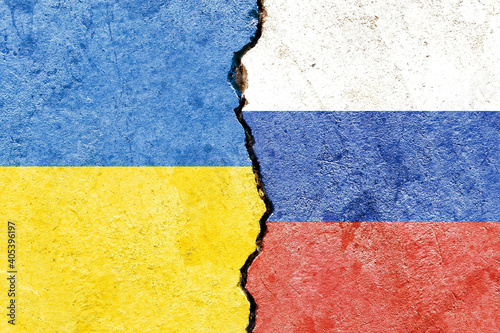 View of Ukraine vs Russia flags on cracked concrete wall - political partnership conflicts concept photo