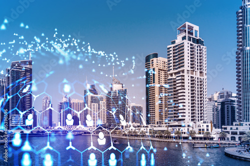 Fototapeta Naklejka Na Ścianę i Meble -  Skyscrapers of Dubai business downtown. International hub of trading and financial services. Social network icons hologram, concept of human resources. Double exposure. Dubai Canal waterfront.