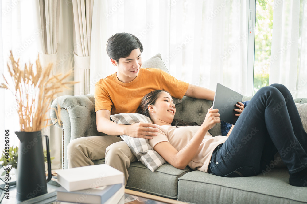© Kris Tan - Happiness young family couple using mobile tablet for relaxing time at home.