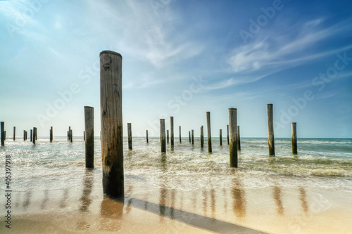 Long exposure seascape. Taken at the North Sea in Petten with the pole village in the sea  Blue sky  sun and shodows
