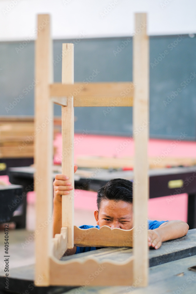 Obraz premium Young carpenter in work clothes assambling components of console table in workshop.