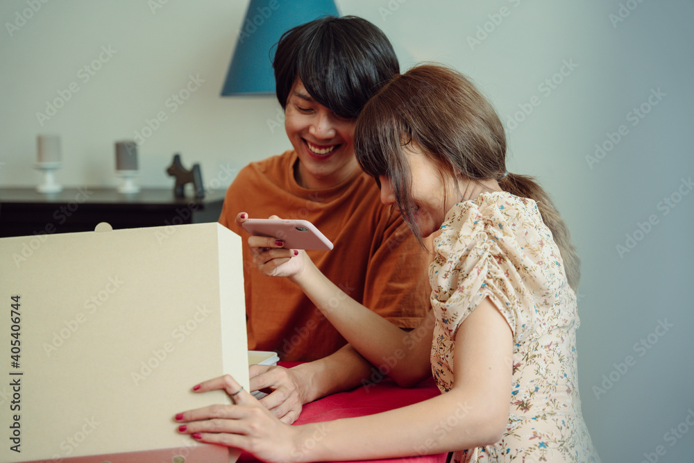 Asian thai couple taking picture of pizza in the box. Asian thai couple taking picture of pizza in the box.