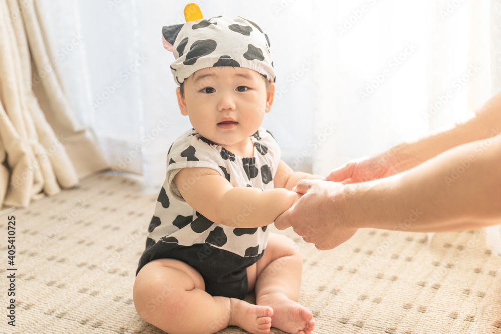 リビングの窓辺で牛のコスプレをして手をつなぐ赤ちゃん