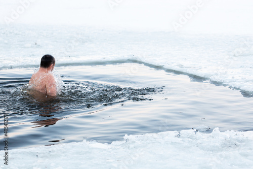 .Traditional swimming in ice water. A man plunges into an ice hole