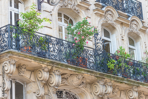 Beautiful parisian building with balcony decorated by flowers