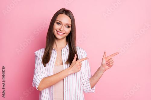 Photo of lovely adorable young woman dressed casual white clothes pointing two fingers empty space isolated pastel pink color background © deagreez