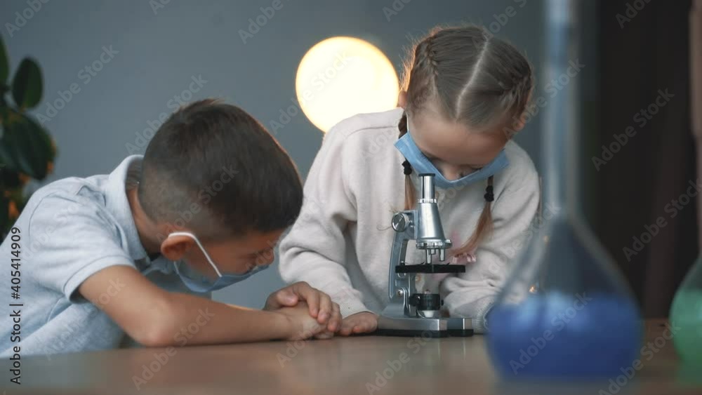 Kids and science. Little boy and girl with face mask using a microscope. Kids and science. Little boy and girl with face mask using a microscope.