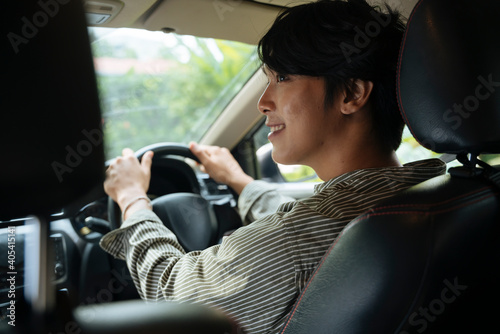 Happy young handsome asian thai man driving a car infront seat.