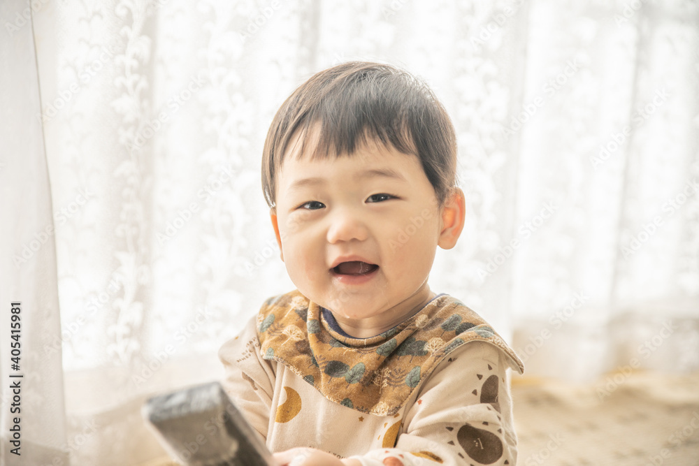 リビングでリモコンで遊ぶ赤ちゃん