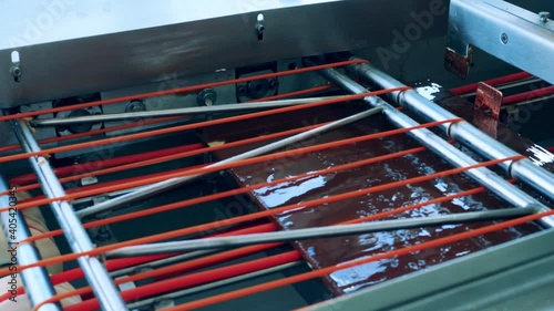 Waffle layers covered in chocolate are moving through the machine photo