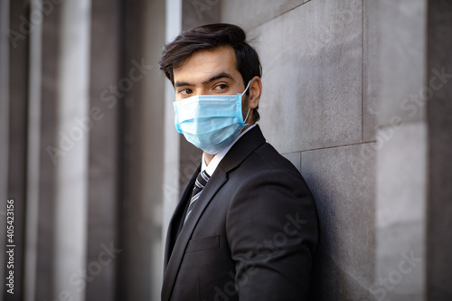 Portrait of a busy caucasian man wearing protective face mask at modern office. Peoples addicted to technology