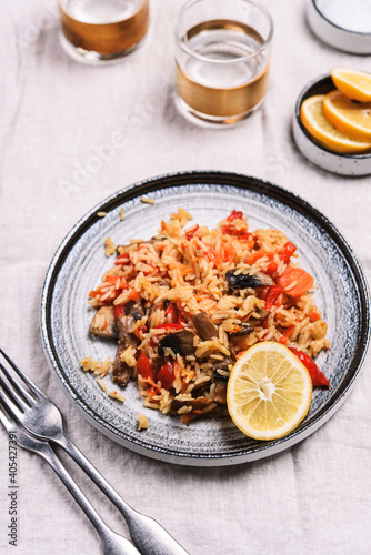 Arroz con verduras y azafran, spanish dish. Vegetarian risotto with  vegetables, champignons and saffron on beige linen tablecloth. Selective focus