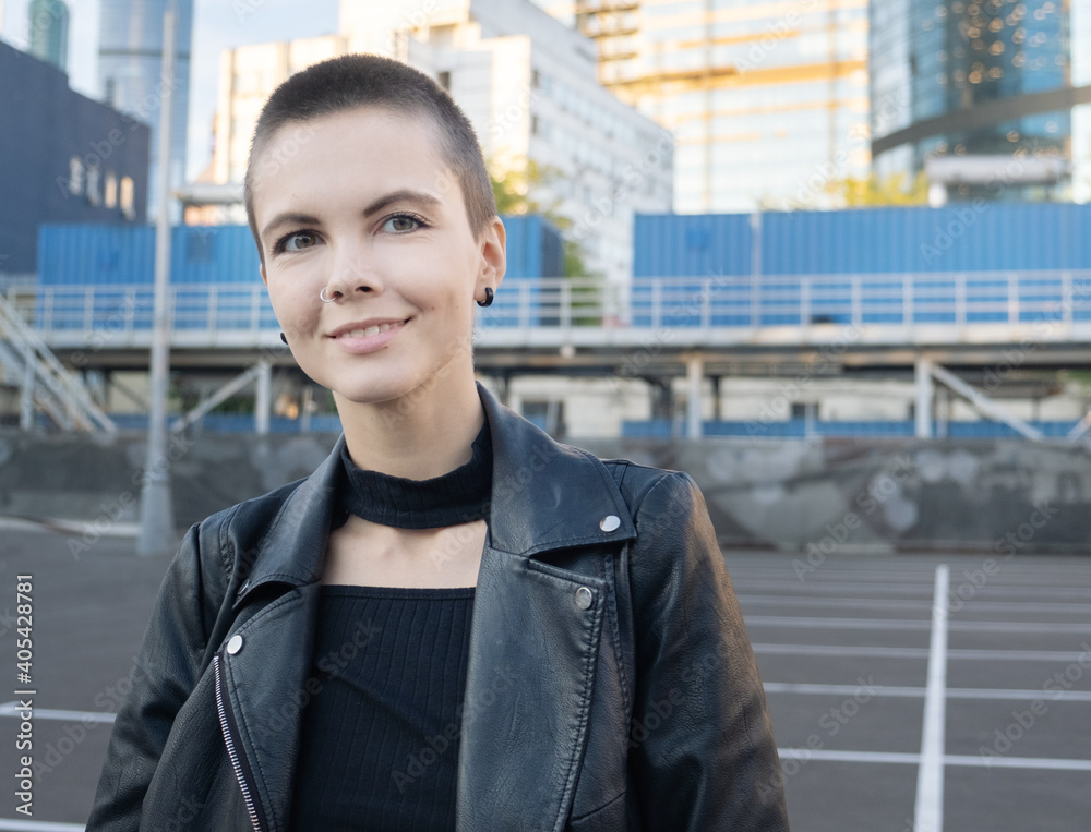 Portrait of smiling young woman with short hair an piercing in industrial city background at sunset. Portrait of smiling young woman with short hair an piercing in industrial city background at sunset.