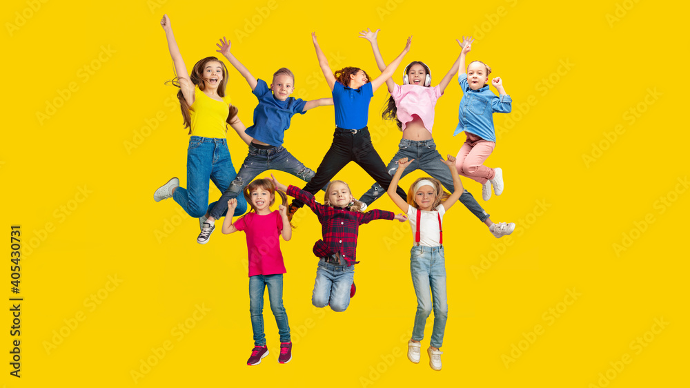 Happy. Portrait of little caucasian children jumping isolated on yellow studio background with copyspace. Cheerful kid models. Concept of human emotions, facial expression, sales, ad, childhood.
