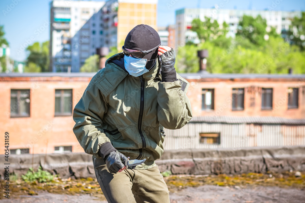 A masked criminal with a knife in his hands is trying to hide from pursuit A masked criminal with a knife in his hands is trying to hide from pursuit