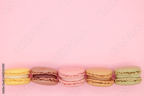 Top view different colors macaroons in row on pink background woth copy space. Valentines day concept, love, surprise, food delivery, sweet table menu