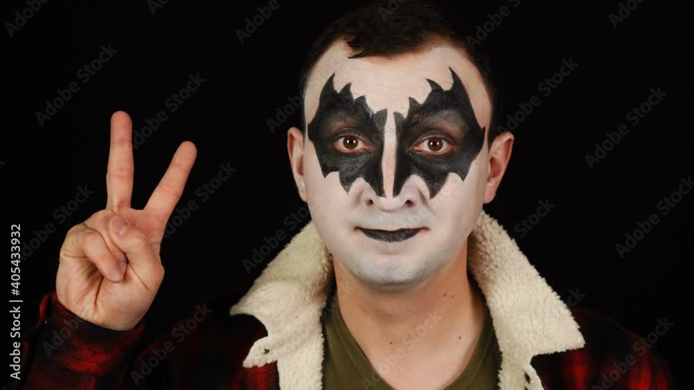 Man in demon makeup showing victory gesture on black background Man in demon makeup showing victory gesture on black background
