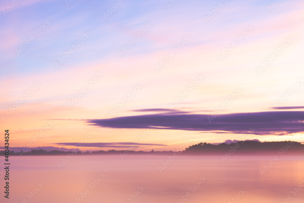 Misty lake landmark at dusk with orange blu sky and purple soft blurry clouds 