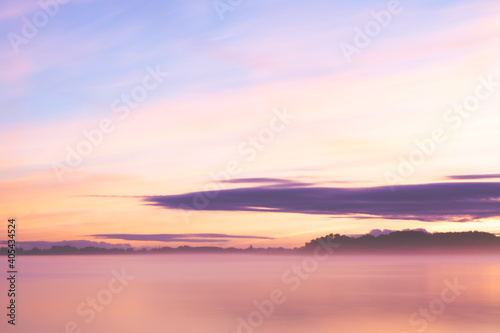 Misty lake landmark at dusk with orange blu sky and purple soft blurry clouds 