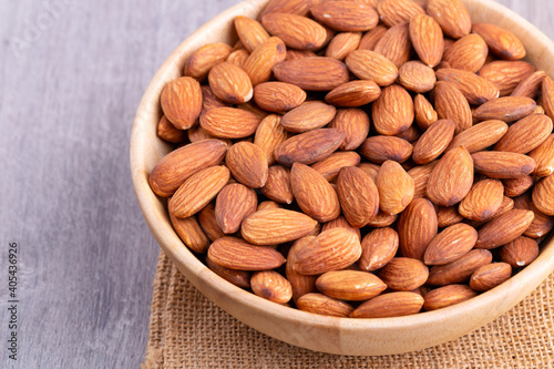 Almonds in wooden bowl on table.