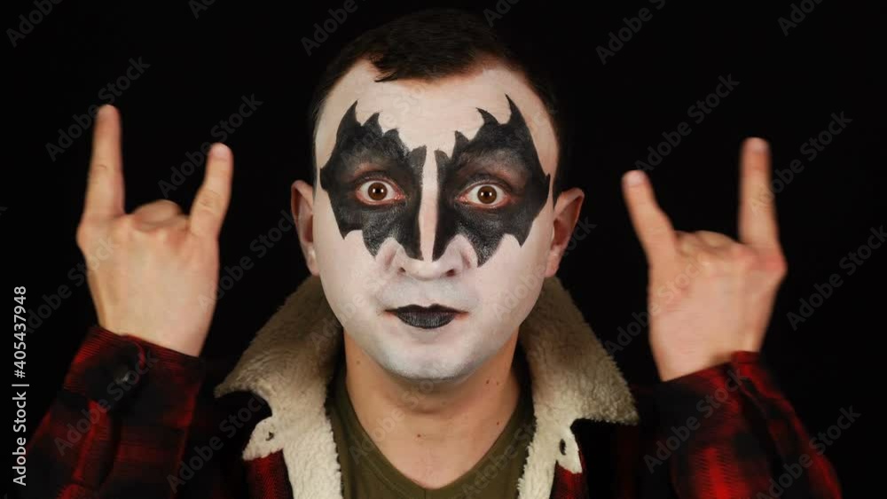 Man in demon makeup showing rock and roll sign, devil horns gesture and looking with crazy expression Man in demon makeup showing rock and roll sign, devil horns gesture and looking with crazy expression