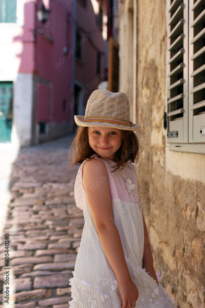 Little cute girl in white dress  posing in the street of Rovinj, Croatia.