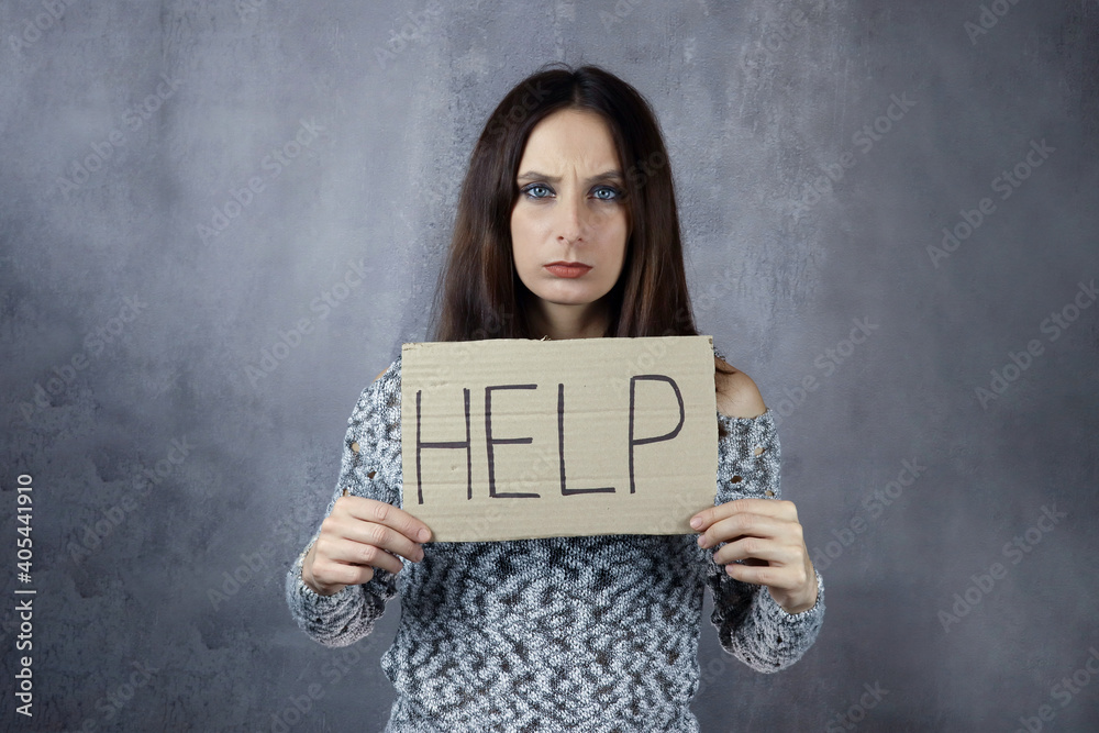 Naklejka premium Cardboard with word help in hands of young woman