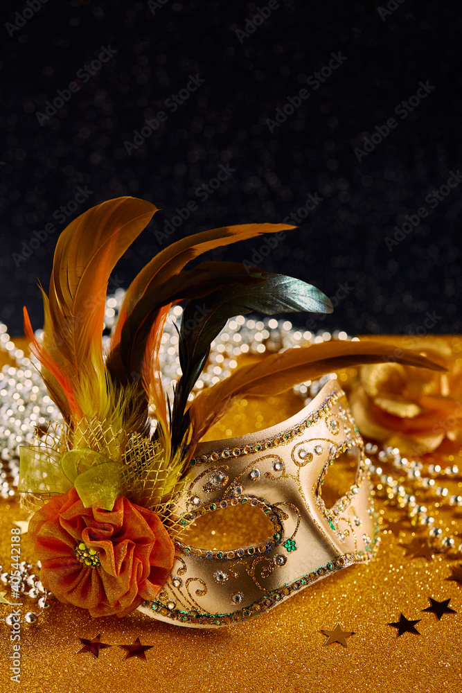 Festive, colorful Mardi Gras or carnivale mask with feathers on golden background. Venetian masks. Party invitation, greeting card, venetian carnivale celebration concept.