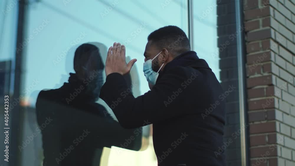 African american man in protective mask looking through window of restaurant, finding out if its open during coronavirus