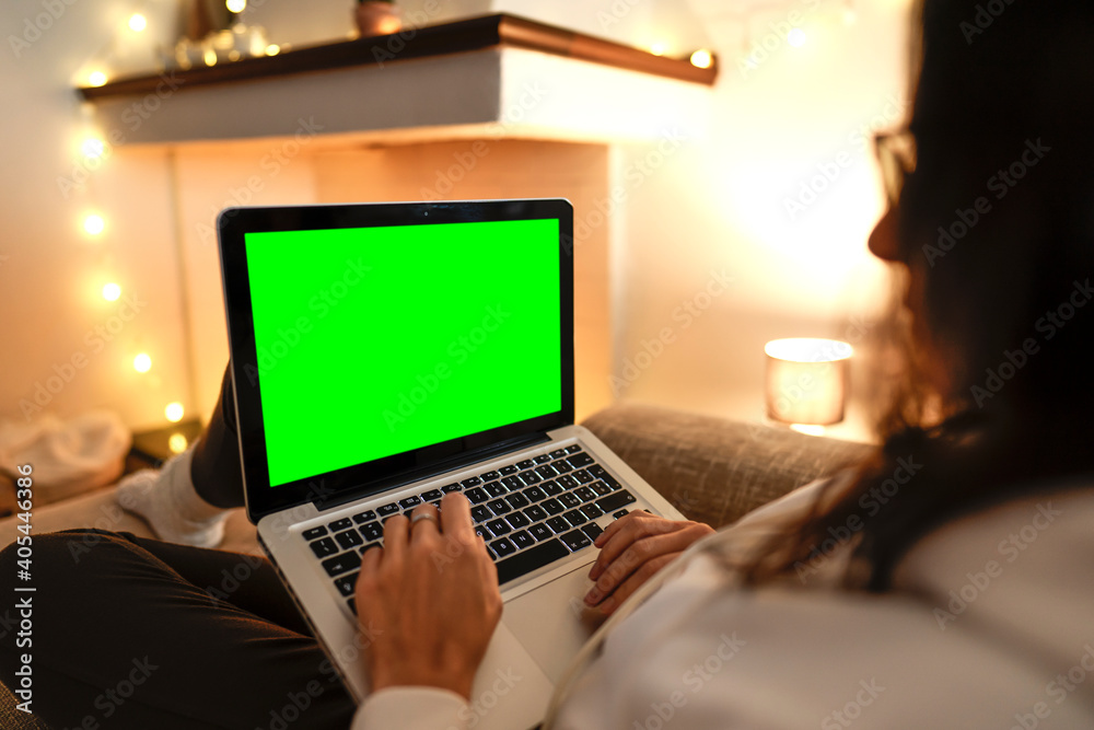 Working from home to change your life: side view close up of young female internet freelance using laptop with blank green screen display comfortably writing at notebook on her sofa. Focus on keyboard Working from home to change your life: side view close up of young female internet freelance using laptop with blank green screen display comfortably writing at notebook on her sofa. Focus on keyboard