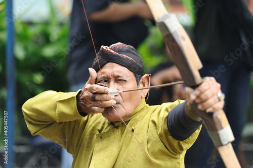 Fototapet Man Aiming While Holding Bow And Arrow With People In Background