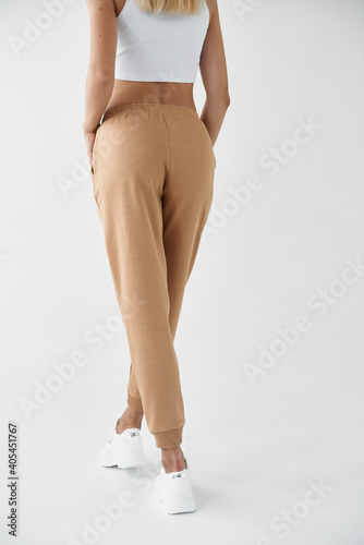 woman wears khaki pants. fit girl is standing in beige joggers