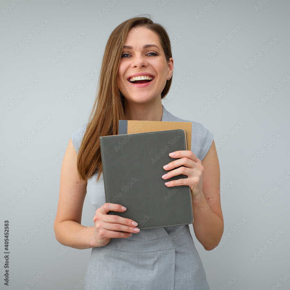 Happy smiling teacher wearing grey dress holding books.