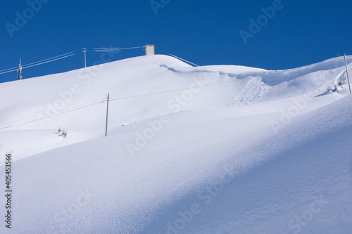 Snowfall. Pristine deep white snow drifts. Sun reflects on the snow in the winter Alps.