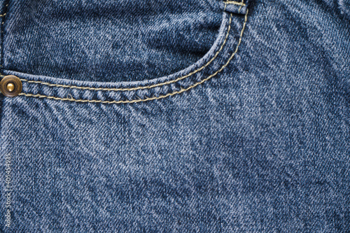 Denim texture fabric with a seam of fashionable design, place for text. Selective focus. Classic jeans background.