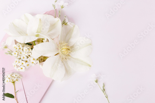 Fototapeta Naklejka Na Ścianę i Meble -  Romantic bouquet of white clematis flowers in a pink envelope, close-up view. Romantic background